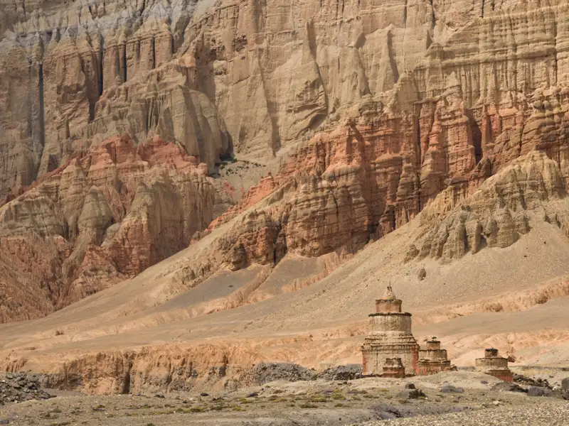 Alte Stupa vor einer imposanten Felswand.