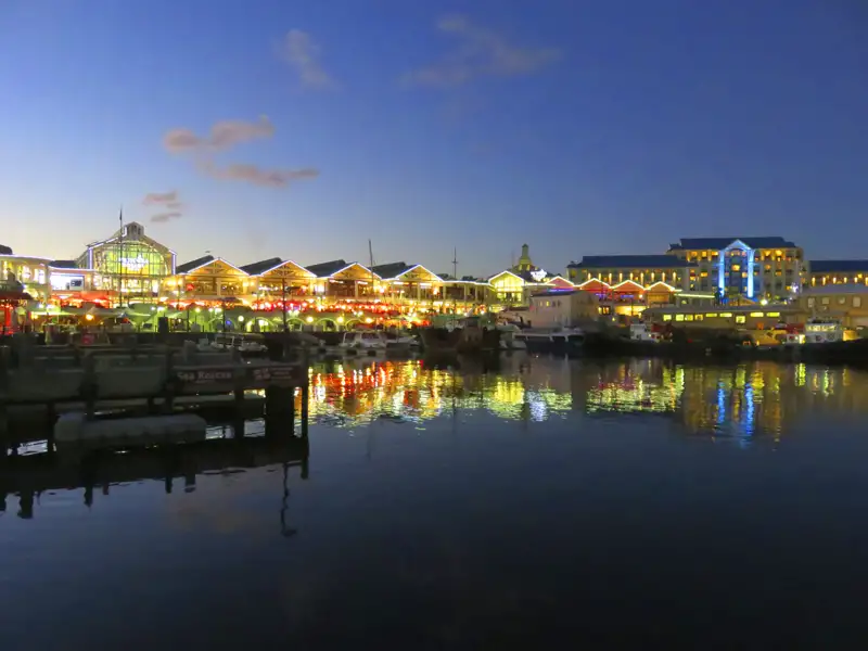 Nachtansicht der V&A Waterfront in Kapstadt mit beleuchteten Gebäuden und Restaurants.
