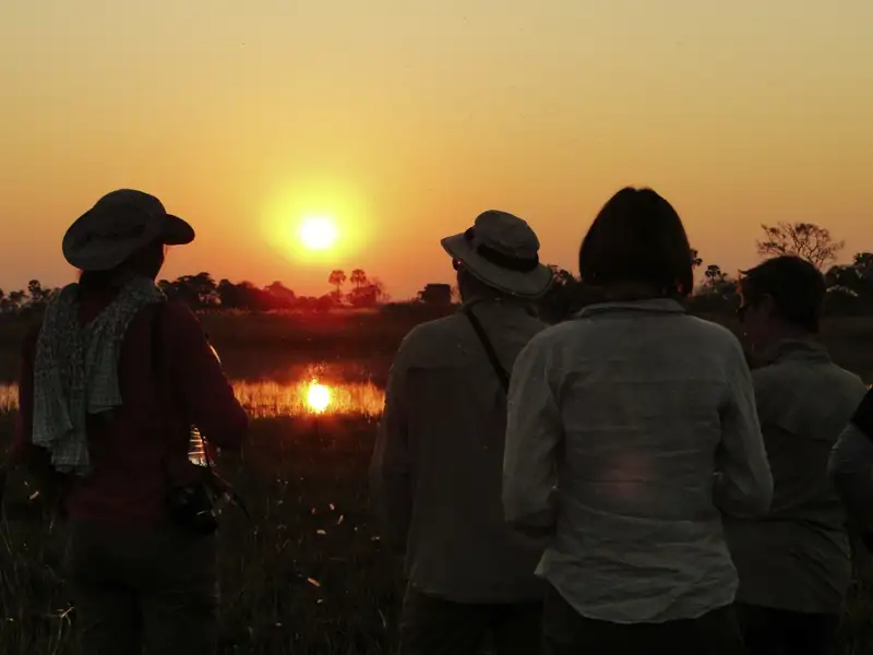 Reisegruppe beim Beobachten des Sonnenuntergangs.