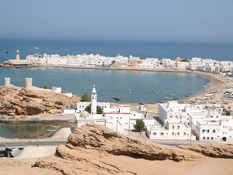Panoramablick auf eine Küstenstadt mit weißer Architektur, einer Moschee und Booten in der Bucht.