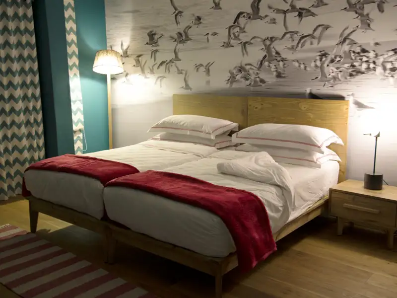 Zwei Einzelbetten in einem Schlafzimmer mit Vogelmotiv an der Wand.