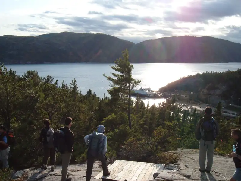 Wanderer auf einem Aussichtspunkt mit Blick auf eine Bucht und eine Fähre.