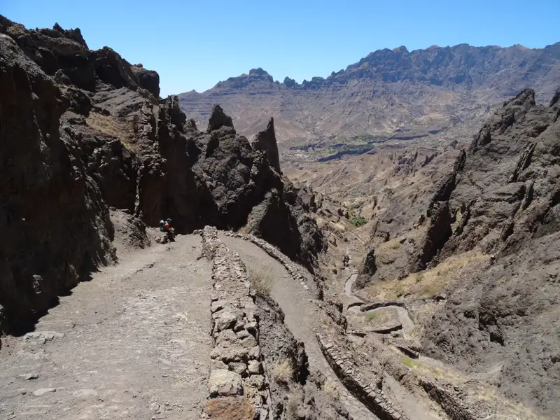 Gewundener Bergpfad in felsiger Landschaft.
