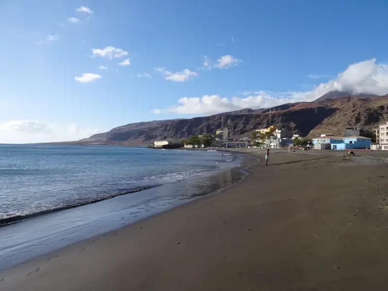 Schwarzer Sandstrand mit Blick auf die Berge.