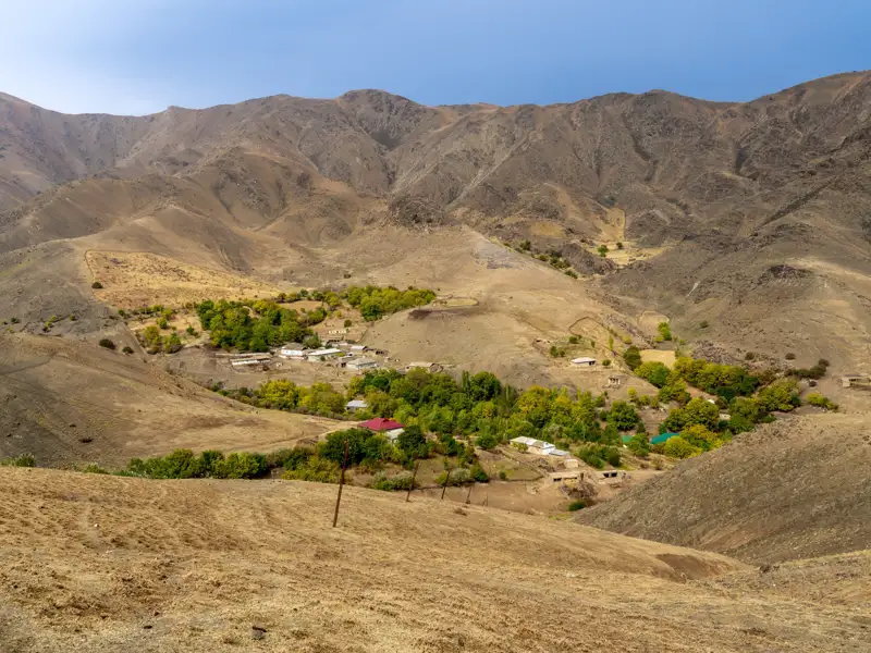 Blick auf ein abgelegenes Bergdorf in einer trockenen Landschaft.