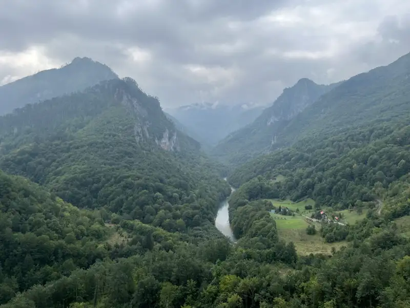 Panoramablick auf ein Flusstal inmitten bewaldeter Berge.