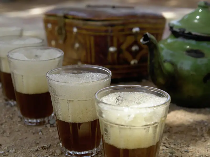 Gläser mit marokkanischem Tee und traditioneller Teekanne.