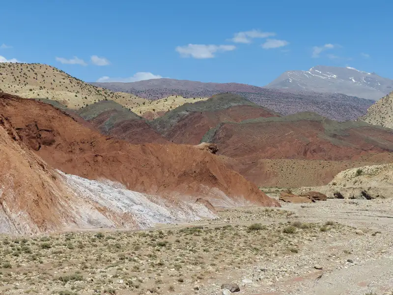 Vielfarbige Gesteinsformationen in einer Berglandschaft unter blauem Himmel.