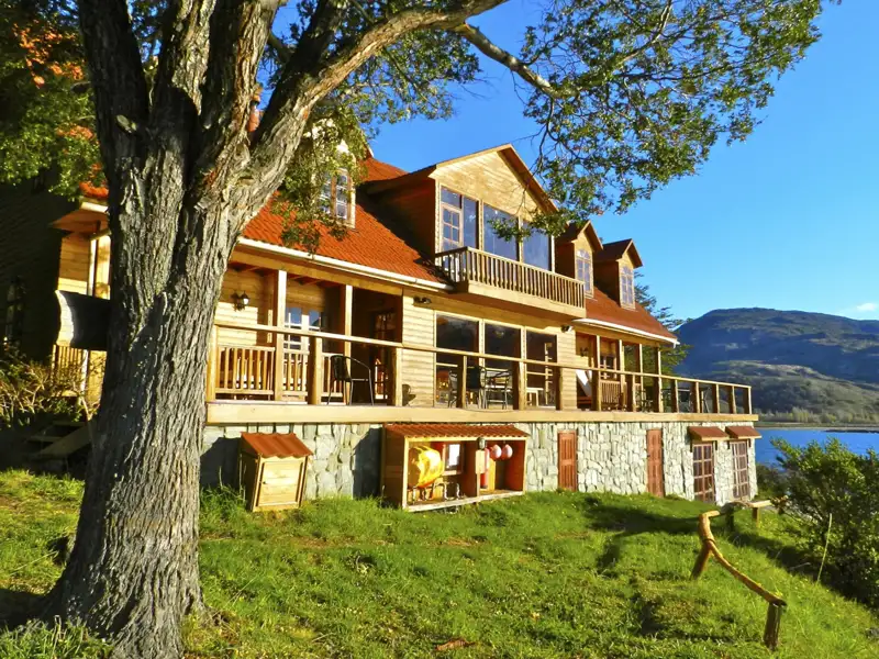 Holzlodge mit Seeblick und Bergen im Hintergrund.