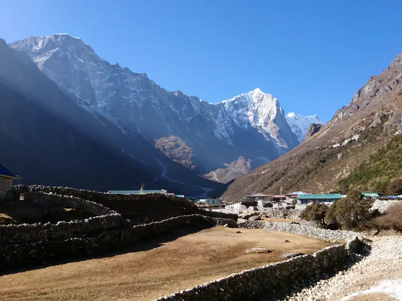 Bergdorf im Himalaya mit schneebedeckten Gipfeln im Hintergrund.