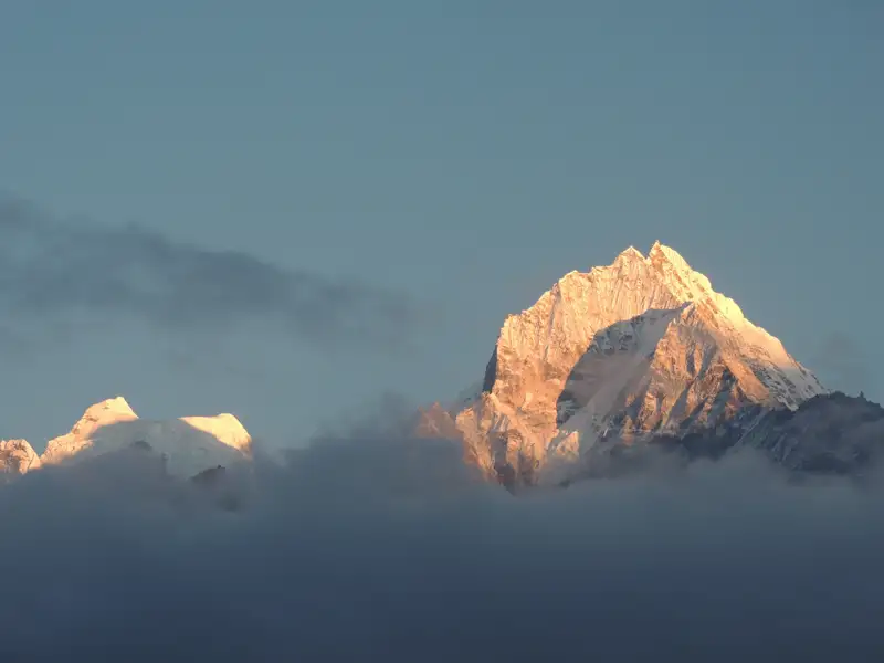 Schneebedeckte Berggipfel, die durch die Wolken scheinen.