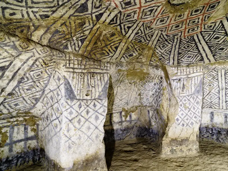 Geometrische Muster in Schwarz, Weiß und Rot an den Wänden und der Decke einer Höhle.