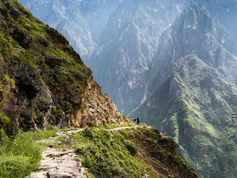 Wanderer auf einem Bergpfad mit Blick auf eine Schlucht.