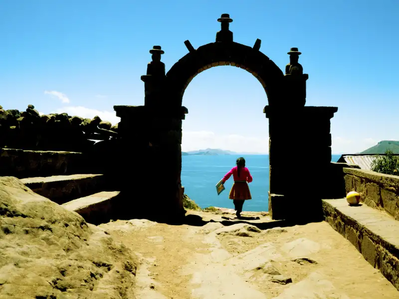 Kind durchschreitet Torbogen mit Blick auf den Titicacasee.