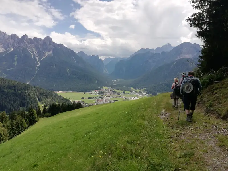 Wanderer auf einem Bergpfad mit Blick auf ein Tal in den Bergen.