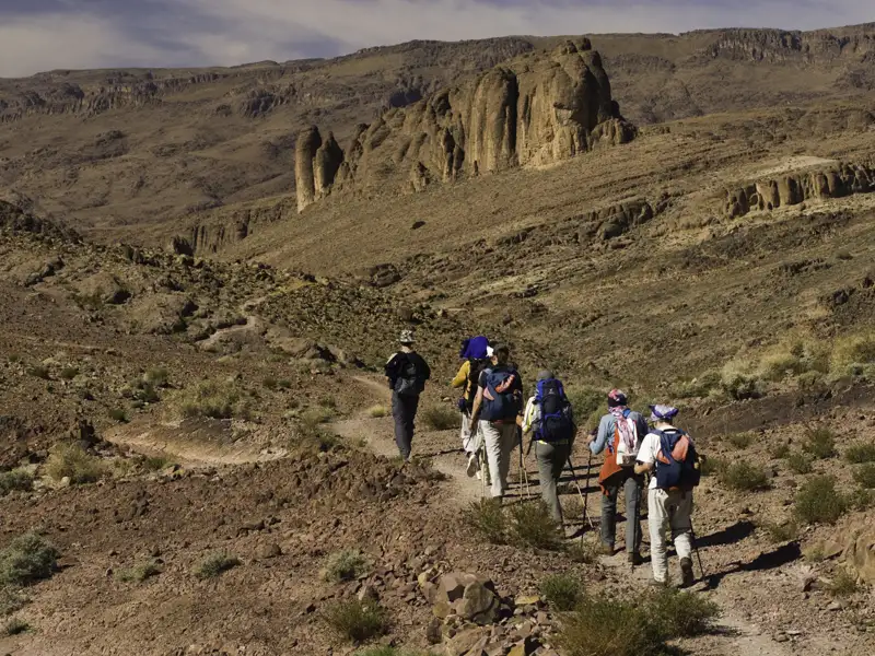 Wanderer auf einem Pfad in einer wüstenartigen Landschaft.