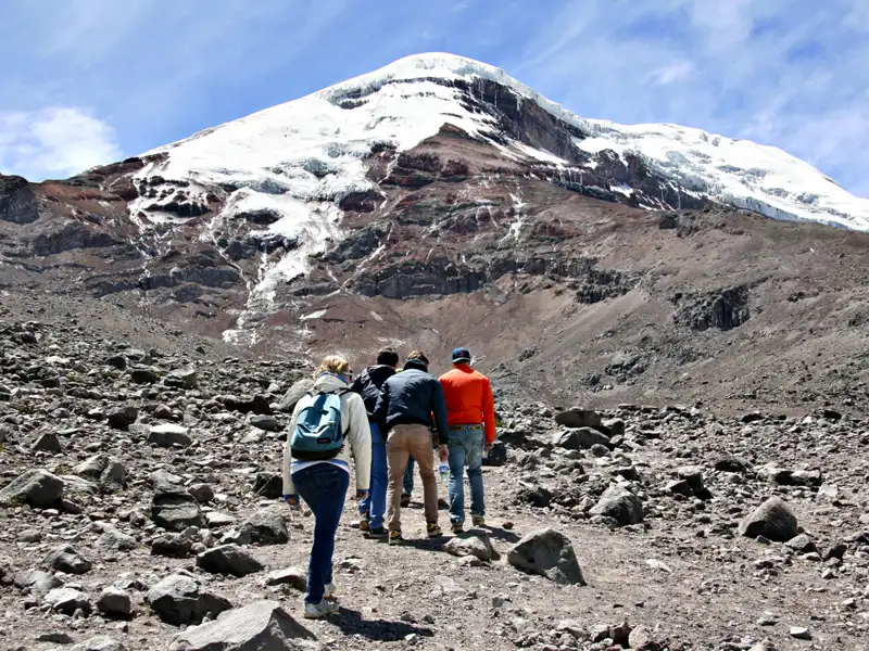 Wanderer auf einer Bergtour nähern sich einem schneebedeckten Gipfel.