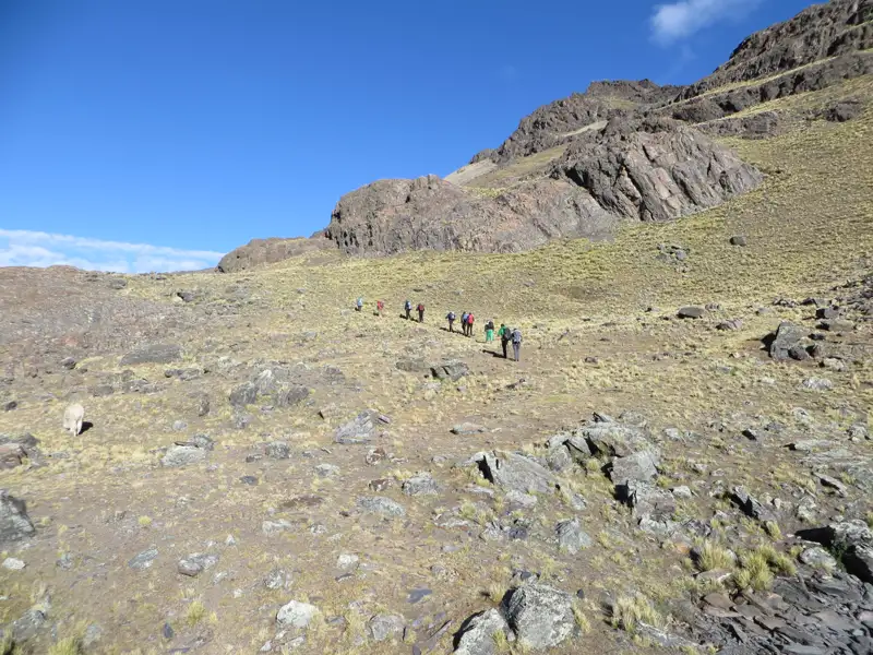 Wandergruppe auf einem Bergpfad in felsiger Landschaft.