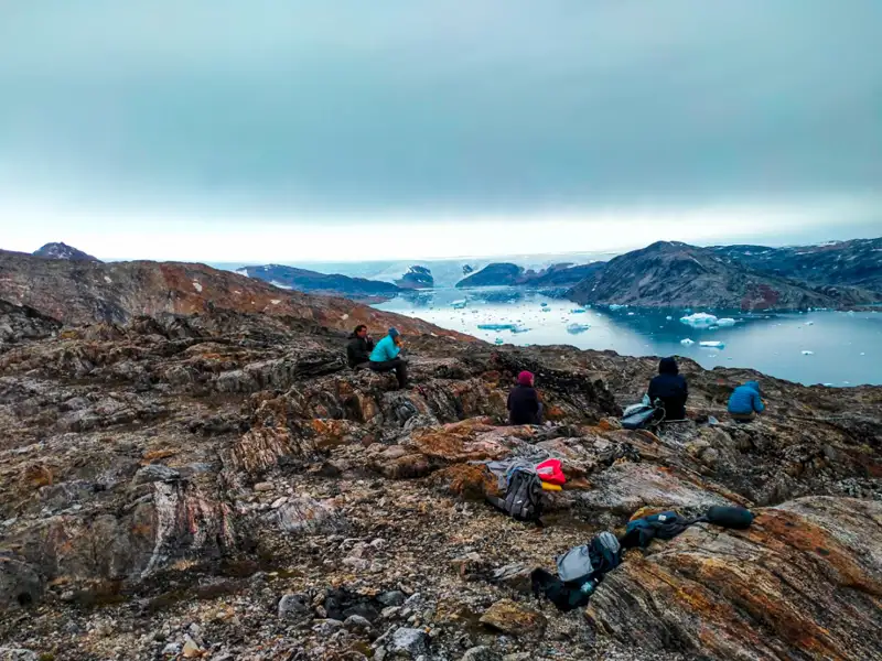 Luftansicht einer grönländischen Siedlung inmitten von Fjorden und schneebedeckten Bergen.