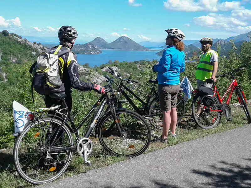 Drei Radfahrer mit Helmen und Fahrrädern halten an und betrachten die Bucht während ihrer Radreise.