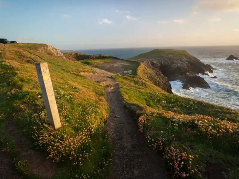 Wegweiser auf einem Küstenwanderweg mit Blick auf das Meer.