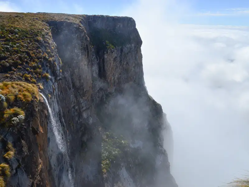 Ein Wasserfall an einer Felswand, umgeben von Wolken.