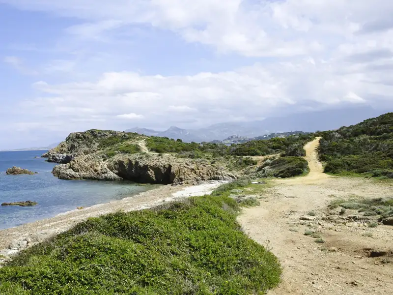 Küstenpfad mit Blick auf das Meer und eine felsige Bucht.
