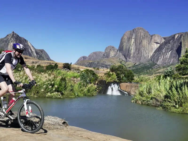 Radfahrer auf einer Reise durch eine bergige Landschaft mit einem Wasserfall.