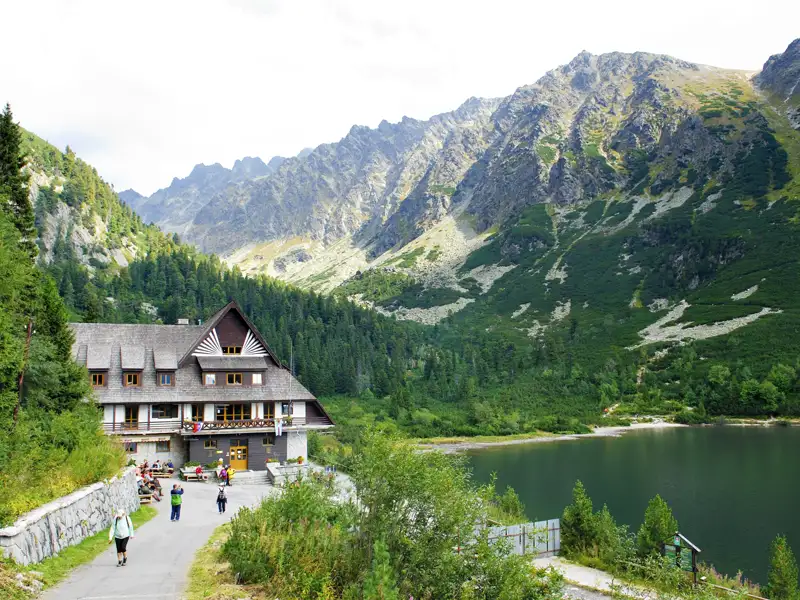 Berghütte am See mit umliegender Berglandschaft.