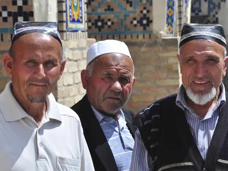 Drei Männer in traditioneller Kleidung, möglicherweise während einer kulturellen Begegnung auf der Reise.