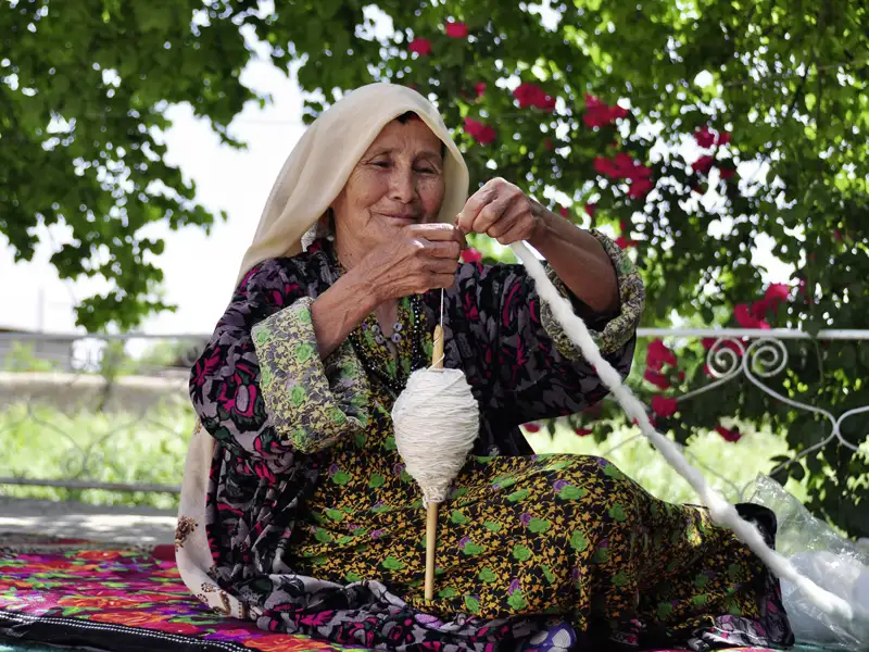 Frau beim Wolle spinnen.