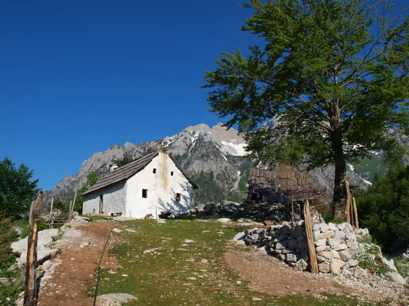Weißes Haus und Hütte in einer Berglandschaft.