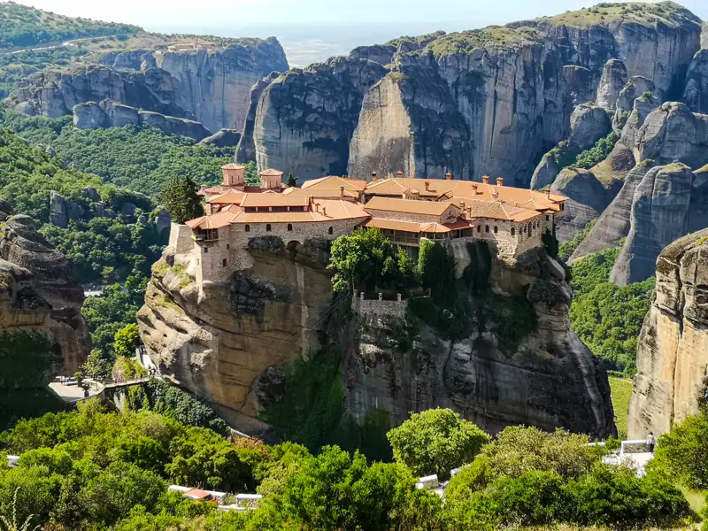 Ein historisches Kloster in Meteora, erbaut auf einem hohen Felsen, mit Blick auf die umliegende Landschaft.
