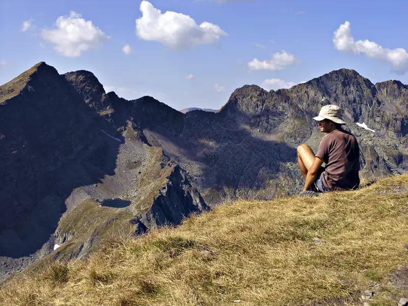 Wanderer pausiert auf einem Berggipfel und betrachtet die Berglandschaft.
