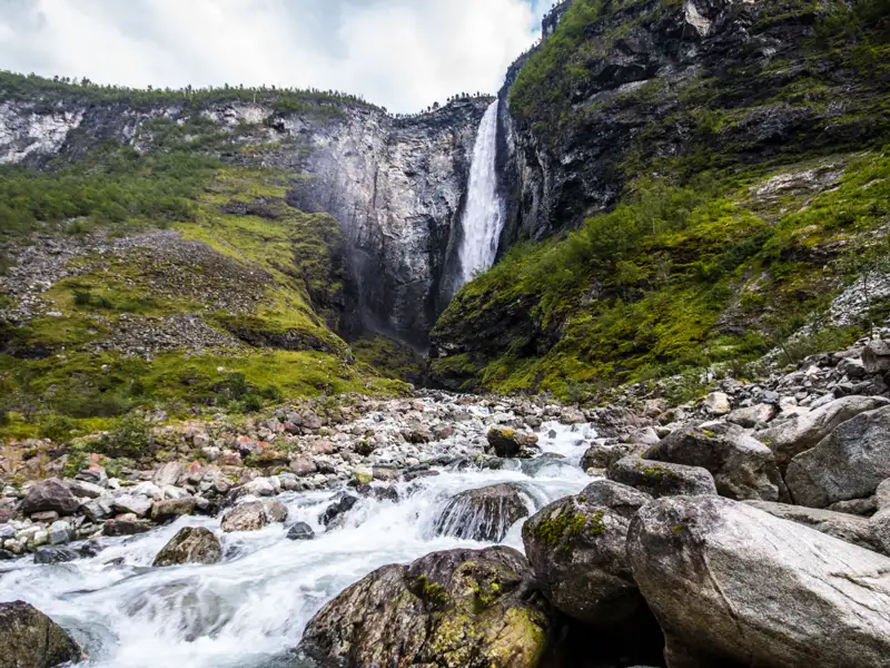 Spektakulärer Wasserfall, der über eine steile Felswand in einen schnell fließenden Fluss stürzt.