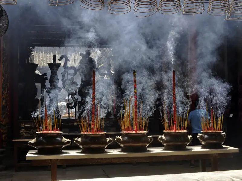 Rauchschwaden von Räucherstäbchen in einem Tempel.