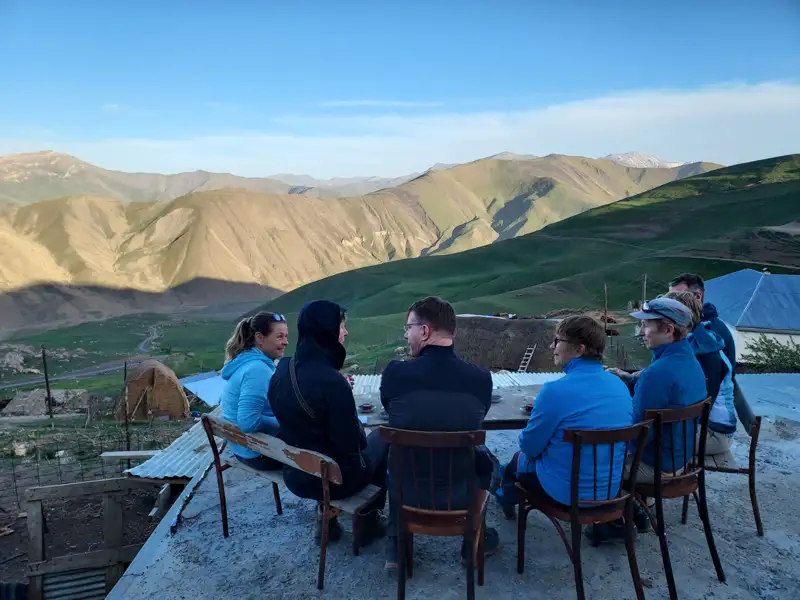 Gruppe von Reisenden entspannt sich auf einer Dachterrasse und genießt den Ausblick auf die Berglandschaft.