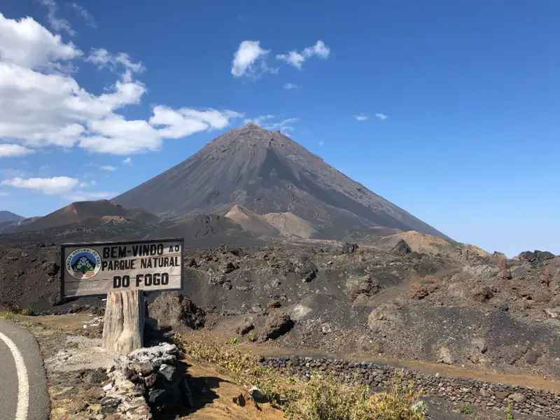 Willkommensschild am Eingang zum Parque Natural do Fogo mit dem Vulkankegel im Hintergrund.