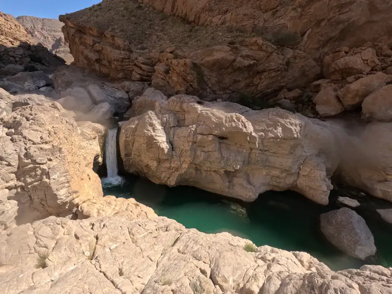 Wasserfall in felsiger Schlucht mit türkisfarbenem Becken.