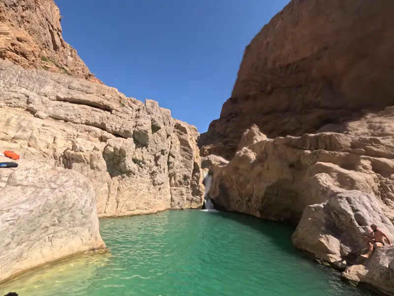 Wasserfall und türkisfarbener Pool in einer felsigen Schlucht.