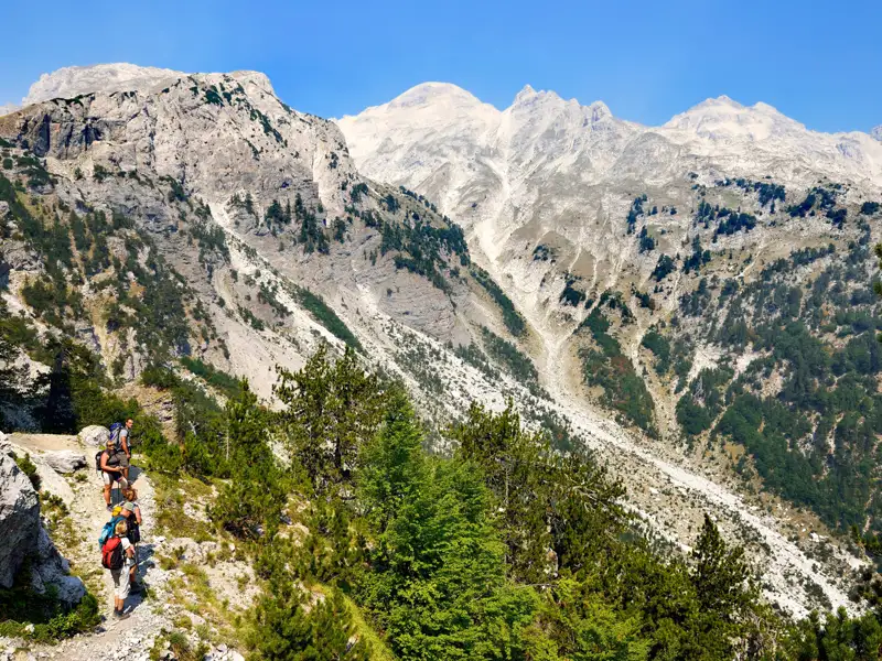 Wanderer auf einem Bergpfad inmitten einer imposanten Bergkulisse.