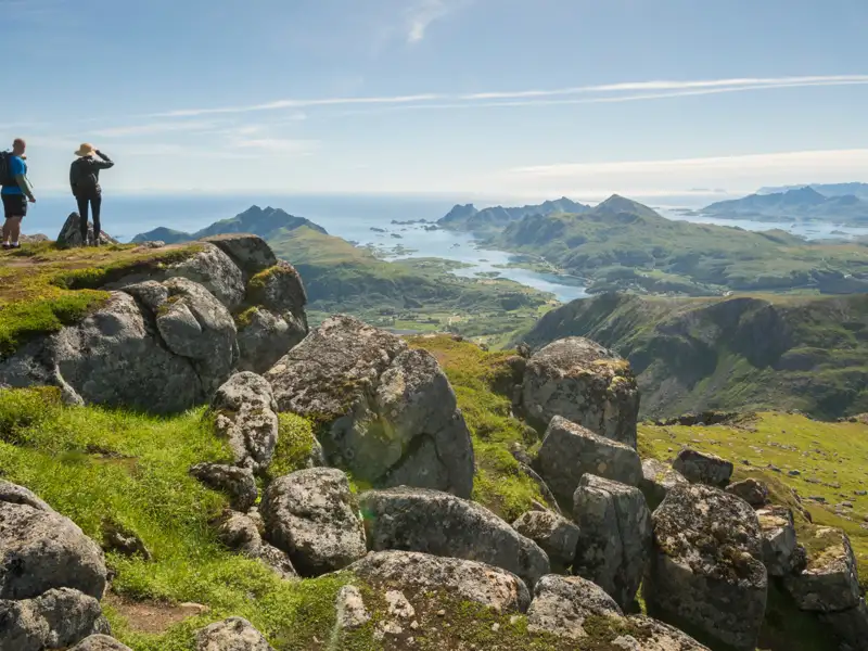 Wanderer auf einem Berggipfel mit Blick auf die Küstenlandschaft.
