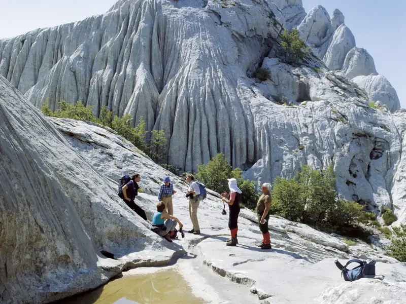 Wanderer machen eine Pause vor einer zerklüfteten Felsformation während ihrer Wanderung.