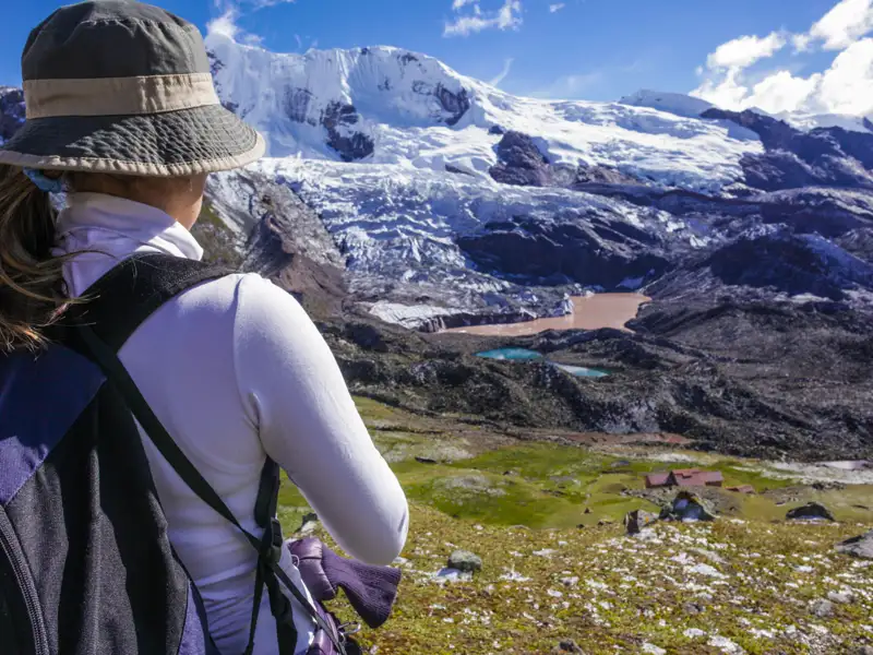 Wanderin bewundert die Aussicht auf einen Gletscher und die darunterliegenden Seen.
