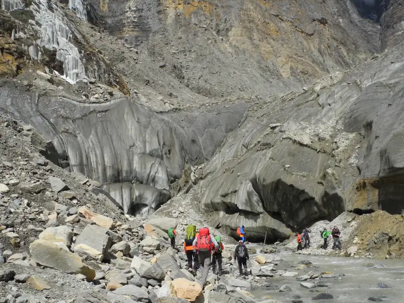 Wanderer auf einem Gletscherpfad neben einem Bach.