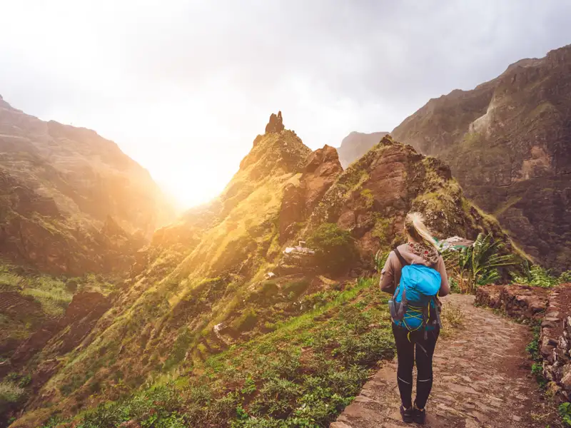 Wanderer auf einem Bergpfad im Sonnenuntergang.