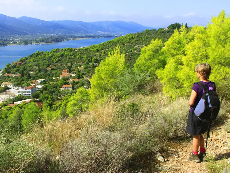 Wanderer auf einem Küstenpfad mit Blick auf das Meer und die Berge.