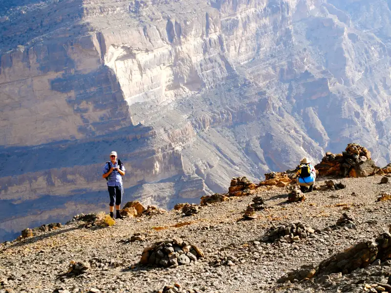 Wanderer am Rande eines tiefen Canyons mit Blick auf die Landschaft.