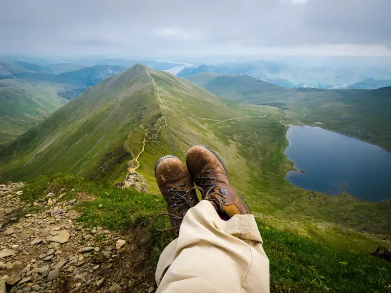 Aussicht vom Gipfel auf einen Bergsee und die umliegende Berglandschaft.
