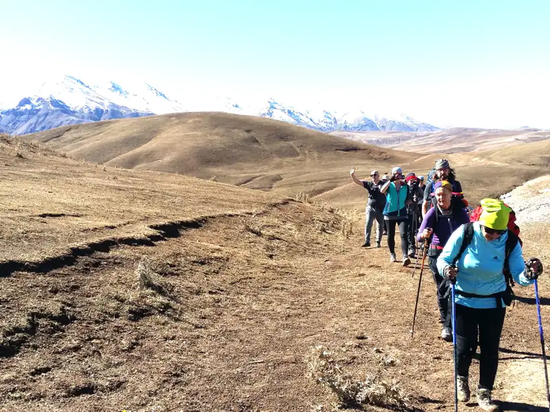 Wandergruppe auf einem Bergpfad mit Blick auf die schneebedeckten Gipfel.